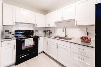 A black oven sits in a kitchen with white cabinets.